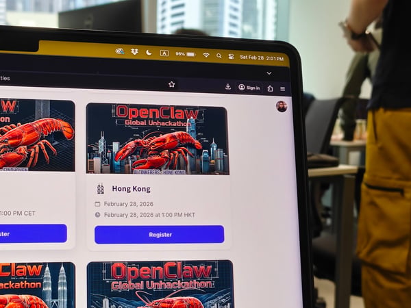 A close-up photograph of a laptop screen displaying a website for 'OpenClaw Global Unhackathon' events in Eindhoven and Hong Kong, with an office setting in the blurred background.