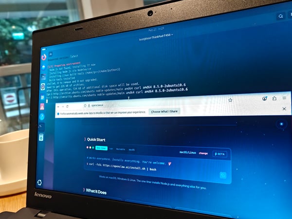 A close-up photo of a Lenovo laptop screen showing a terminal window with installation logs and a web browser open to the openclaw.ai website.