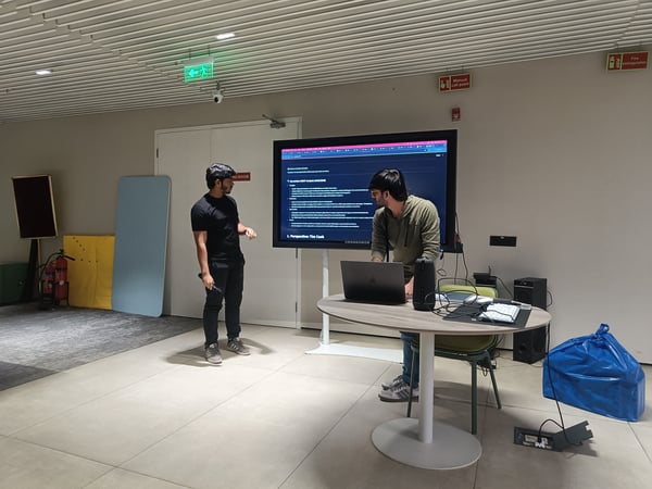 Two men are in a modern meeting room, with one gesturing toward a large screen displaying an Apple Inc. SWOT analysis while the other works on a laptop.