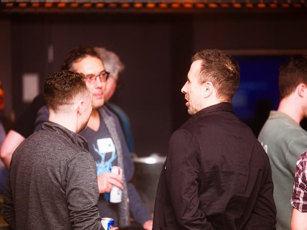 A group of men are engaged in conversation at an indoor social or networking event.