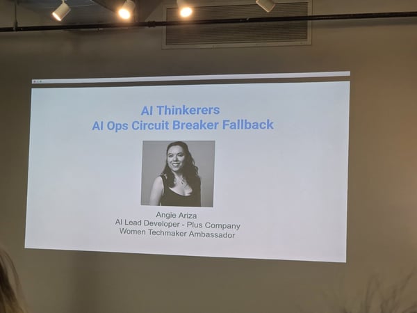 A photograph captures a large projection screen in an indoor venue, displaying the title slide for a presentation titled "AI Ops Circuit Breaker Fallback" by speaker Angie Ariza.