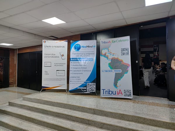 A photograph showing three promotional banners for AI and data services standing on a small set of steps in an indoor hallway, with people visible in the background.