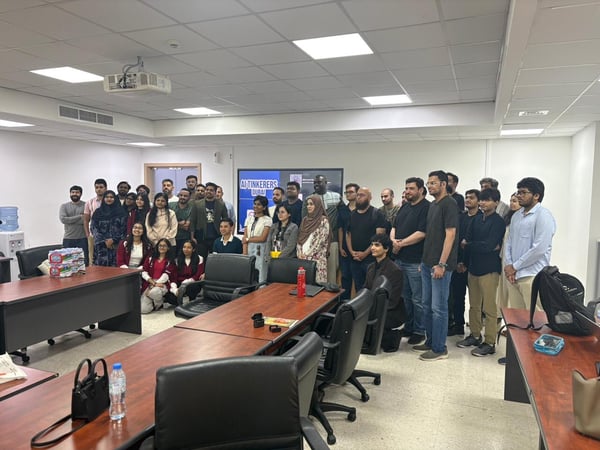A group photo of attendees standing together in a conference room at an AI Tinkerers event in Dubai.