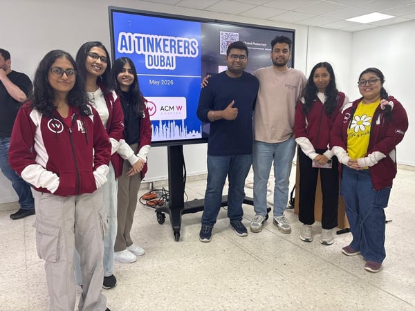 A group of young adults posing for a photo in front of a large display screen at an event.